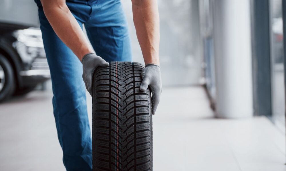 Meccanico che trascina una gomma di un'auto