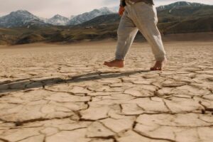 siccità, cambiamento climatico, bambino cammina a piedi nudi su terreno secco
