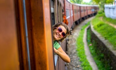 ragazza sorridente che si sporge dal vagone di un treno