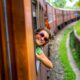 ragazza sorridente che si sporge dal vagone di un treno