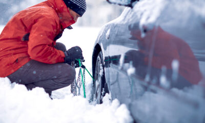 Uomo che tenta di montare le catene da neve alla sua auto