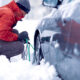 Uomo che tenta di montare le catene da neve alla sua auto