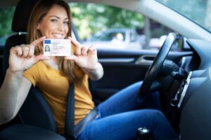 Ragazza felice ce tiene in mano la patente nella sua auto