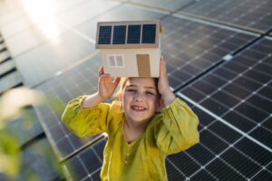 Bambina davanti a una casa con pannelli solari sul tetto