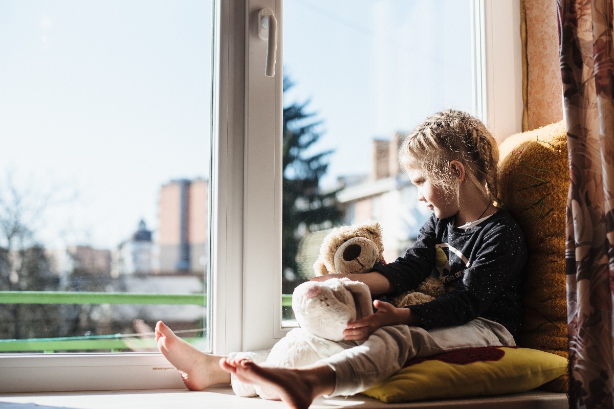 Bambina si affaccia alla finestra di casa