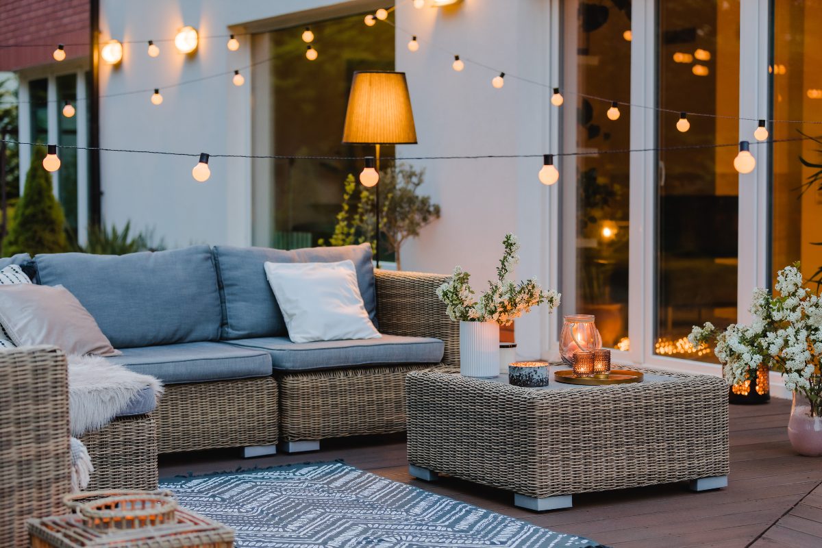 Arredo da esterno con divano e tappeto per un giardino curato in stile estivo