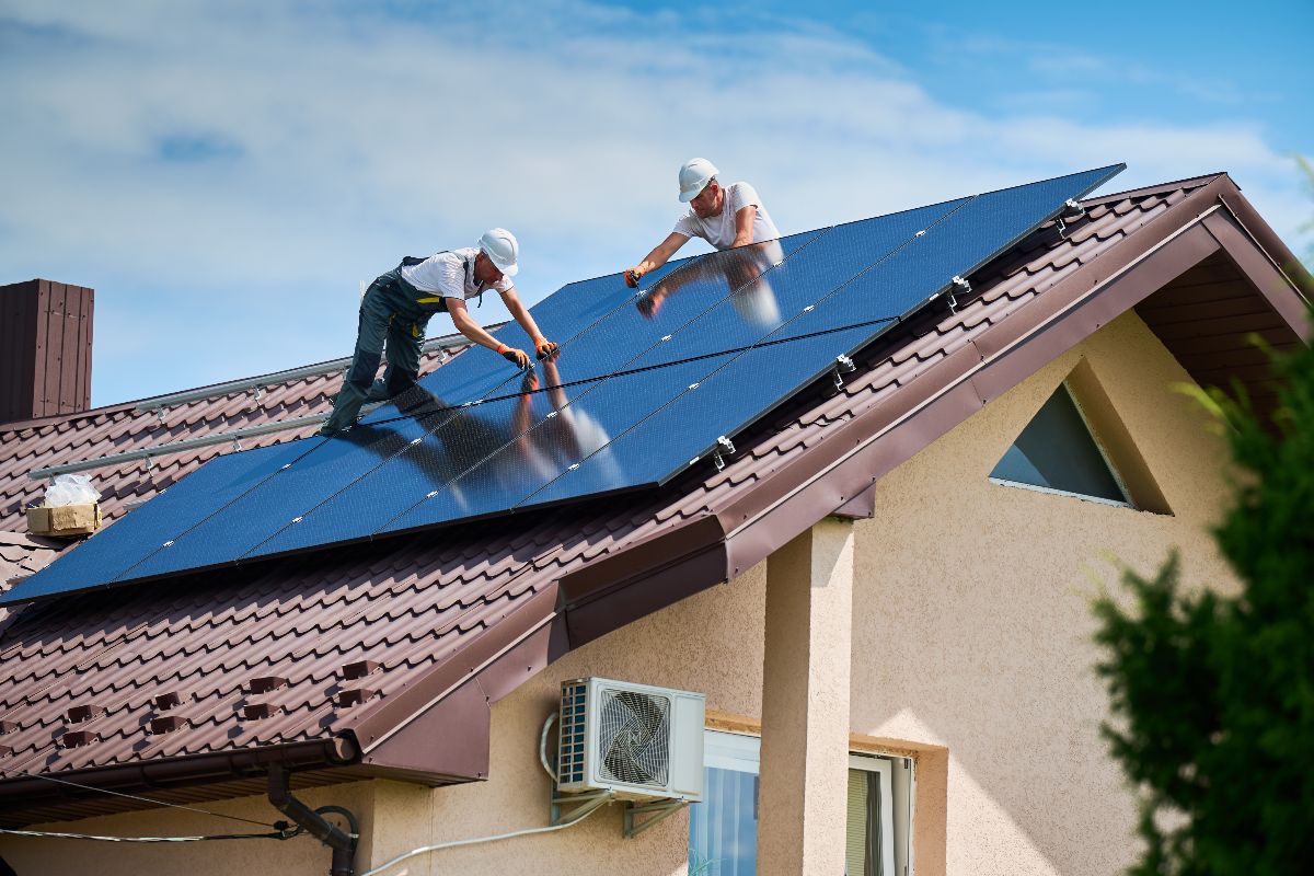 Operai impegnati nell’installazione di pannelli solari sul tetto di un’abitazione.