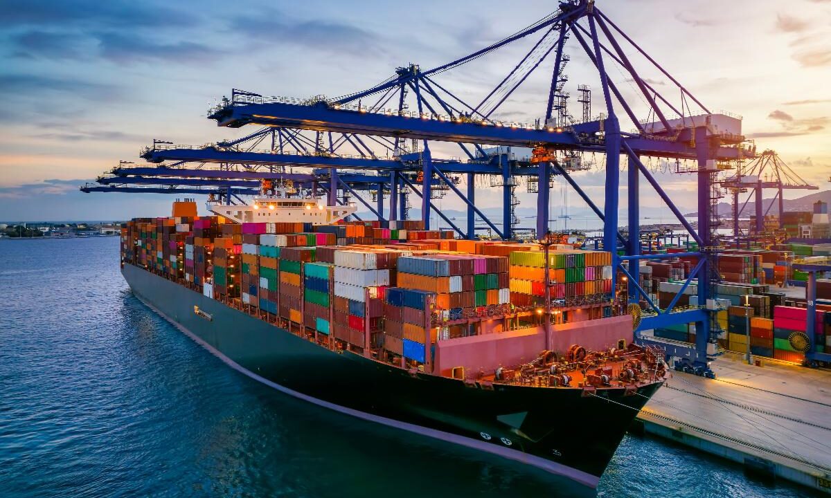 Nave cargo carica di container attraccata in un porto commerciale.