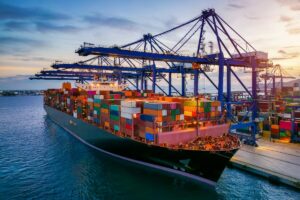 Nave cargo carica di container attraccata in un porto commerciale.
