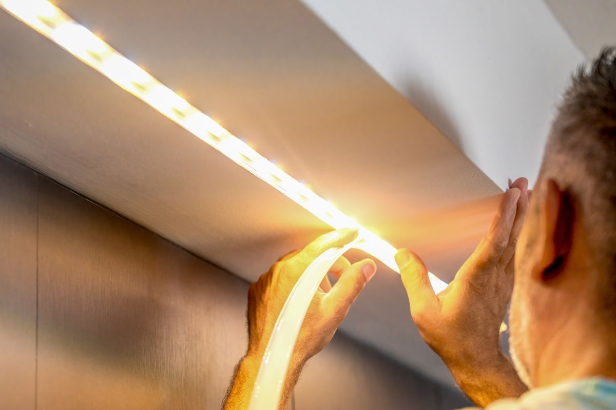 Montaggio luci: un uomo intento a installare una striscia a LED.