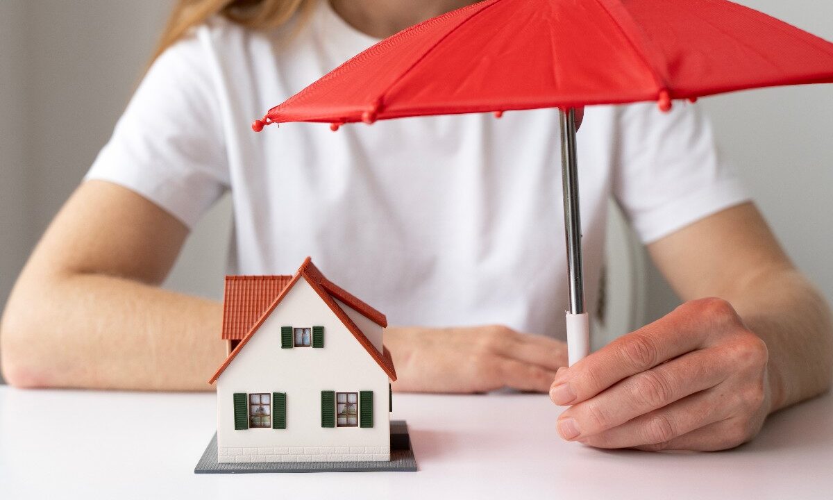 Icona della casa protetta da un ombrello contro eventi atmosferici.
