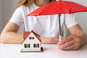 Icona della casa protetta da un ombrello contro eventi atmosferici.