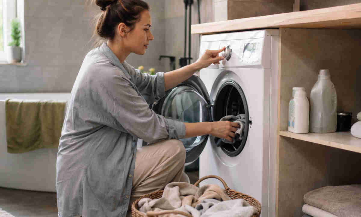 Ragazza che fa il bucato con un lavaggio veloce alla lavatrice