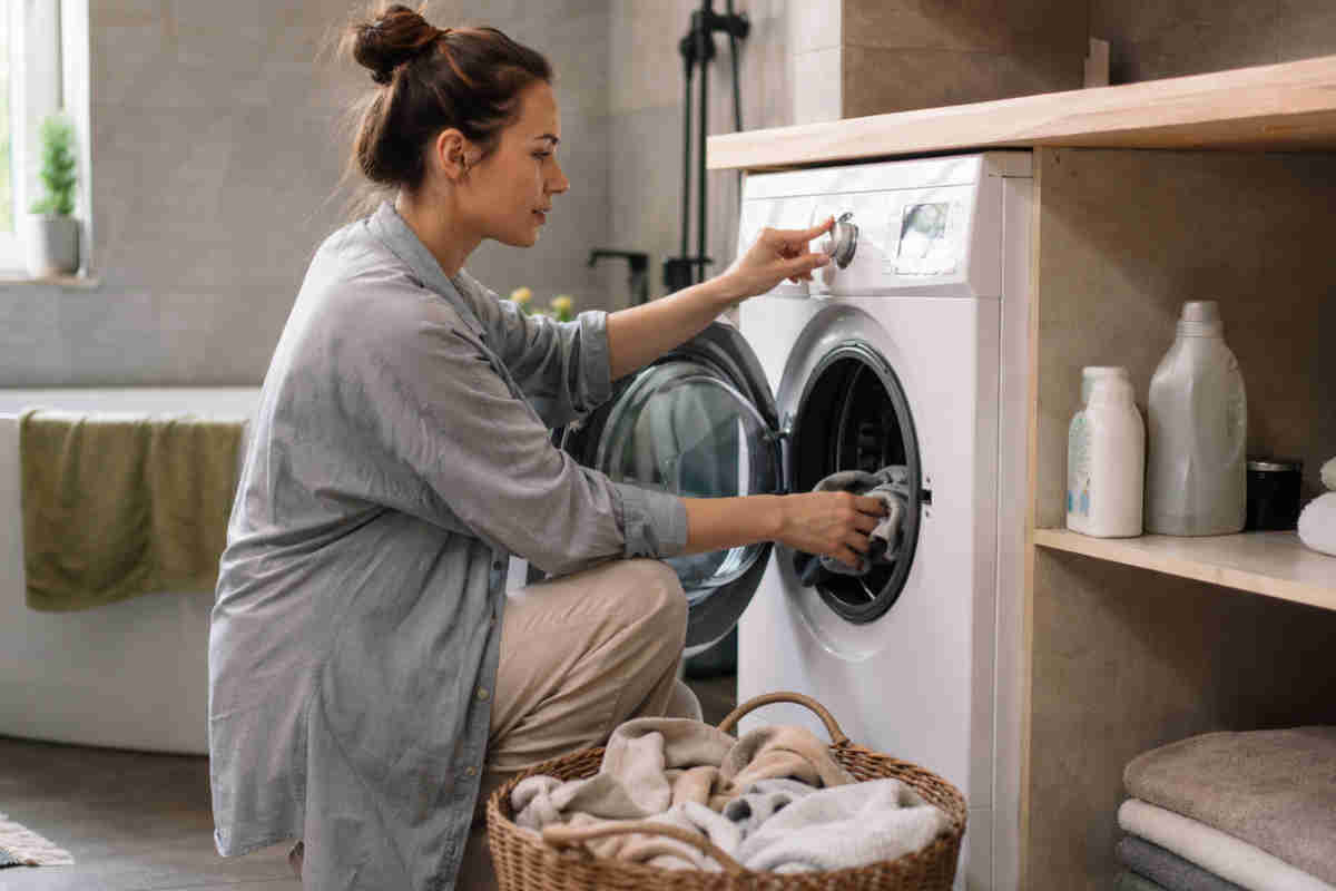 Ragazza che fa il bucato con un lavaggio veloce alla lavatrice